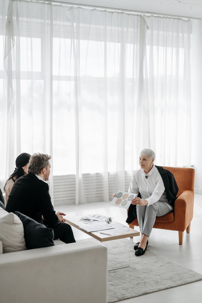 Mastering the First Impression: Your intriguing post title goes here Three adults in a modern minimalist room engaged in a consultation meeting.